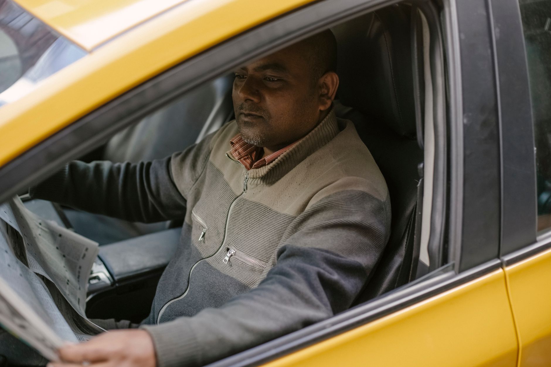 Motorista dirigindo um táxi amarelo pela cidade
